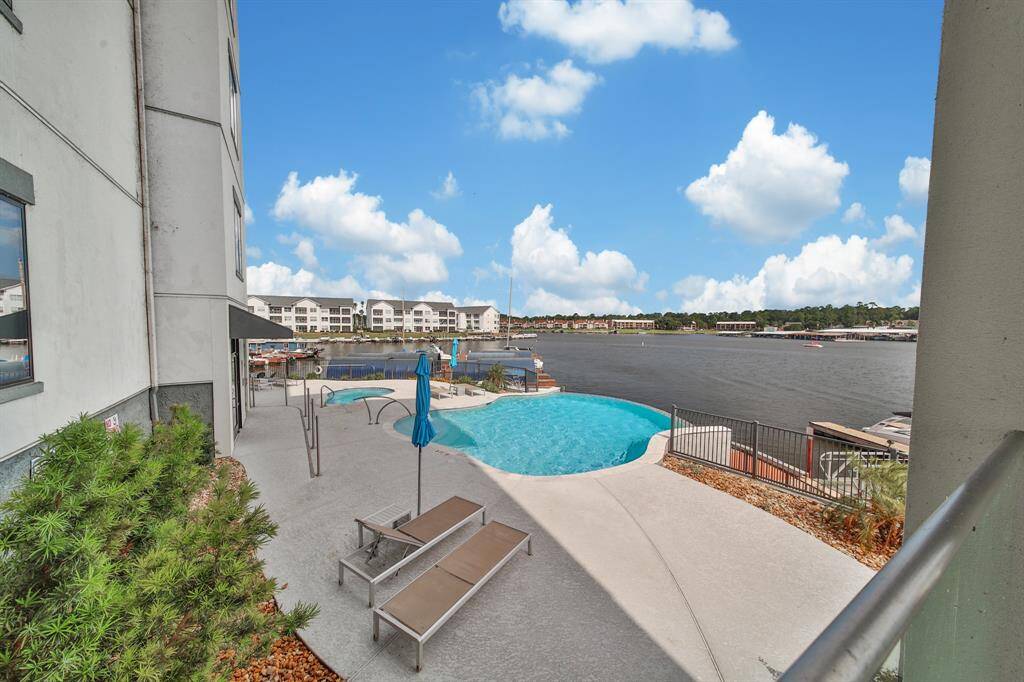 This photo showcases a community pool area with a waterfront view, offering a relaxing ambiance and outdoor recreational space, part of a residential complex.