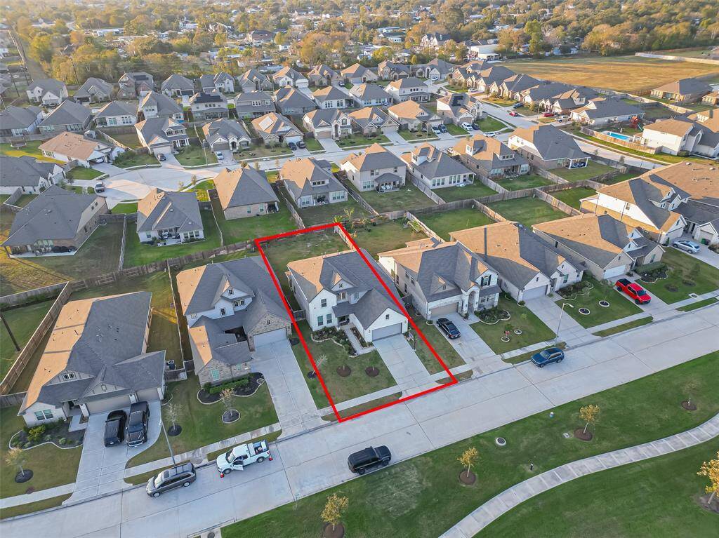 This photo showcases a modern two-story house highlighted in red within a suburban neighborhood. It features a driveway, well-maintained lawn, and is situated in a community with similar homes, offering a tidy and cohesive environment.