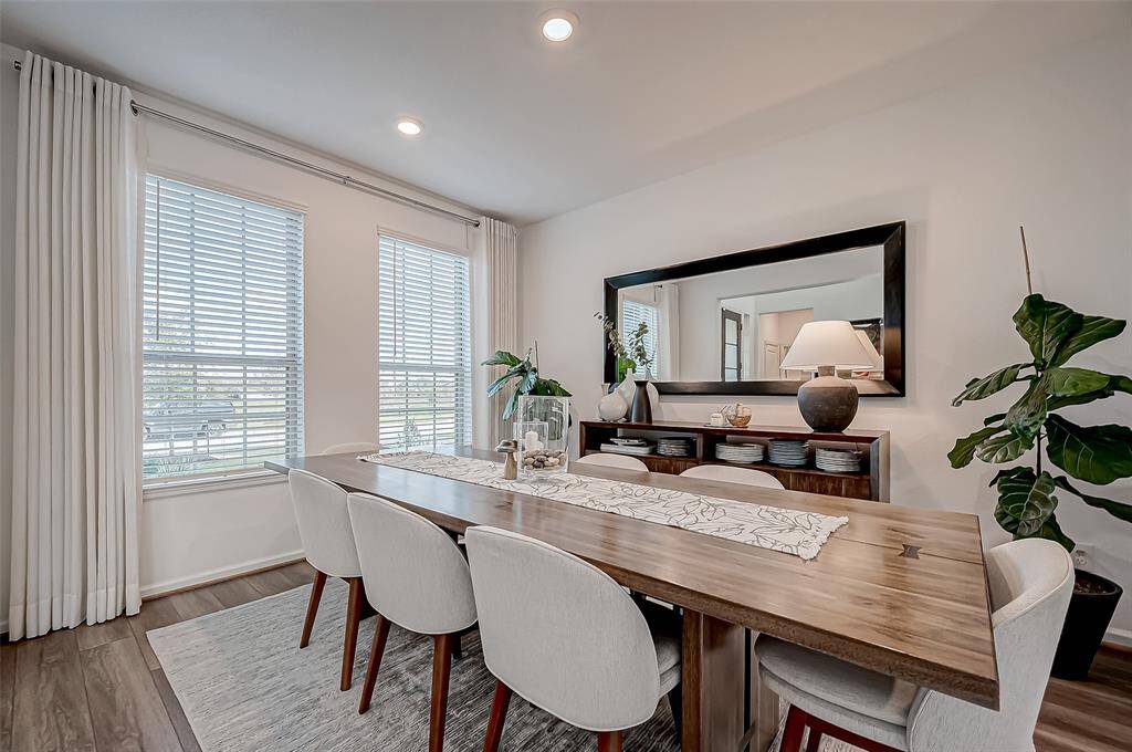 Bright dining room with large windows decorated with elegant wooden table with seating for eight. A stylish sideboard, decorative mirror, and modern lighting is complete for entertaining. (All furniture excluded)