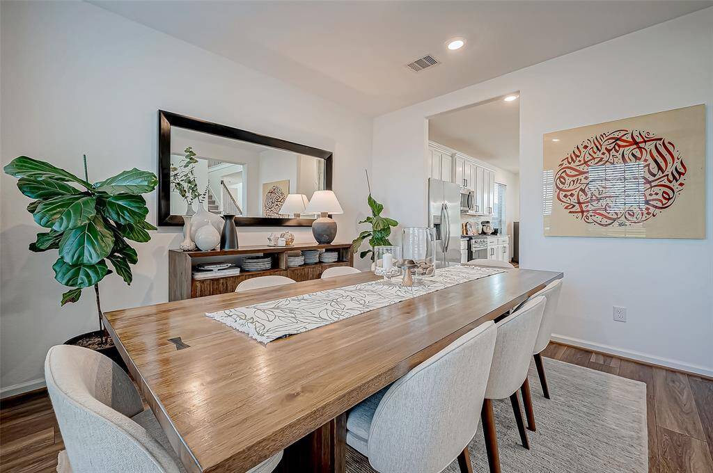This dining room offers a modern and inviting space decorated with large wooden table, upholstered chairs, and tasteful decor. It features a large mirror, stylish artwork, and ample natural light from an adjoining kitchen area. Perfect for entertaining and family meals. ( Furniture excluded from the sale)