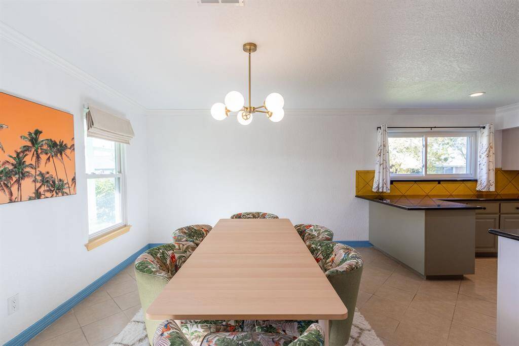 Large tiled formal dining room.  Kitchen to the right. Crown molding and baseboards.