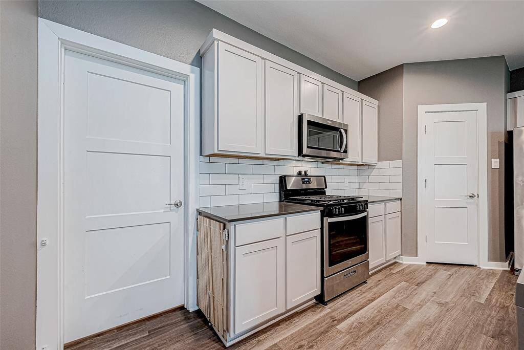 Discover the kitchen's elegance featuring a stylish tile backsplash, a modern gas range, and convenient access to a spacious pantry.