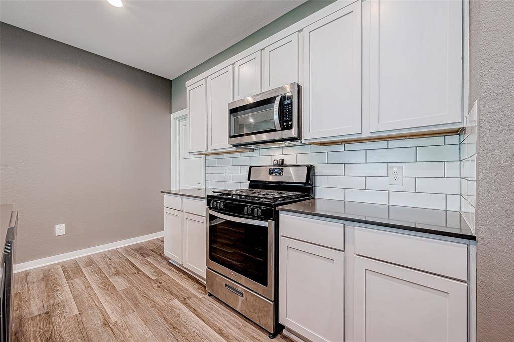 Sleek subway tile backsplash and modern cabinets complement the gas range, enhancing the kitchen's contemporary design.