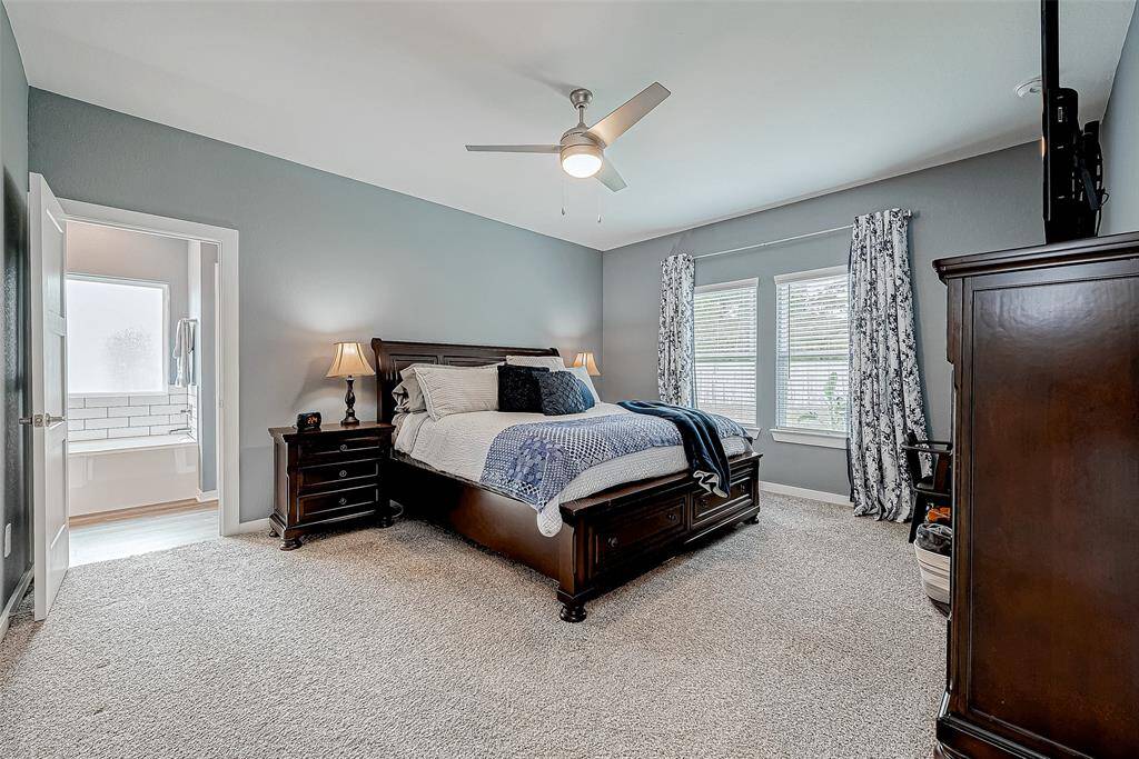 Spacious first-floor primary suite with fresh paint and a stunning backyard pool view adjacent to the well-appointed bathroom.
