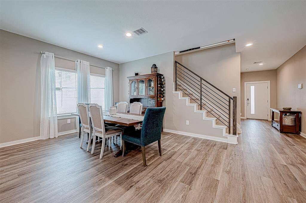 This inviting view from the kitchen showcases a spacious dining area and a modern staircase leading to the front door.