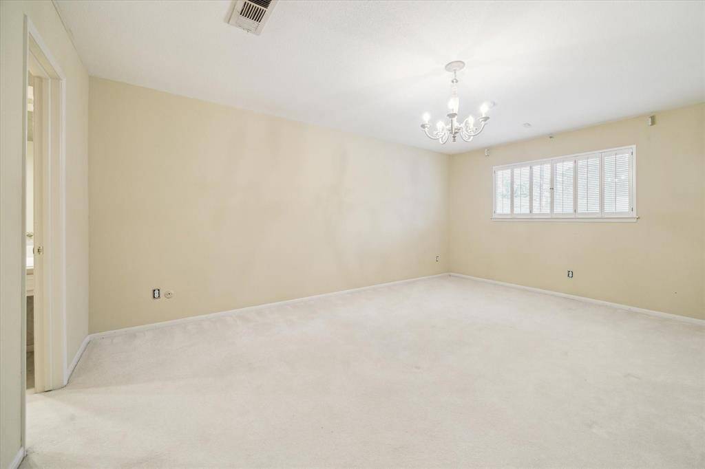 Spacious primary bedroom featuring a stylish chandelier and abundant natural light.