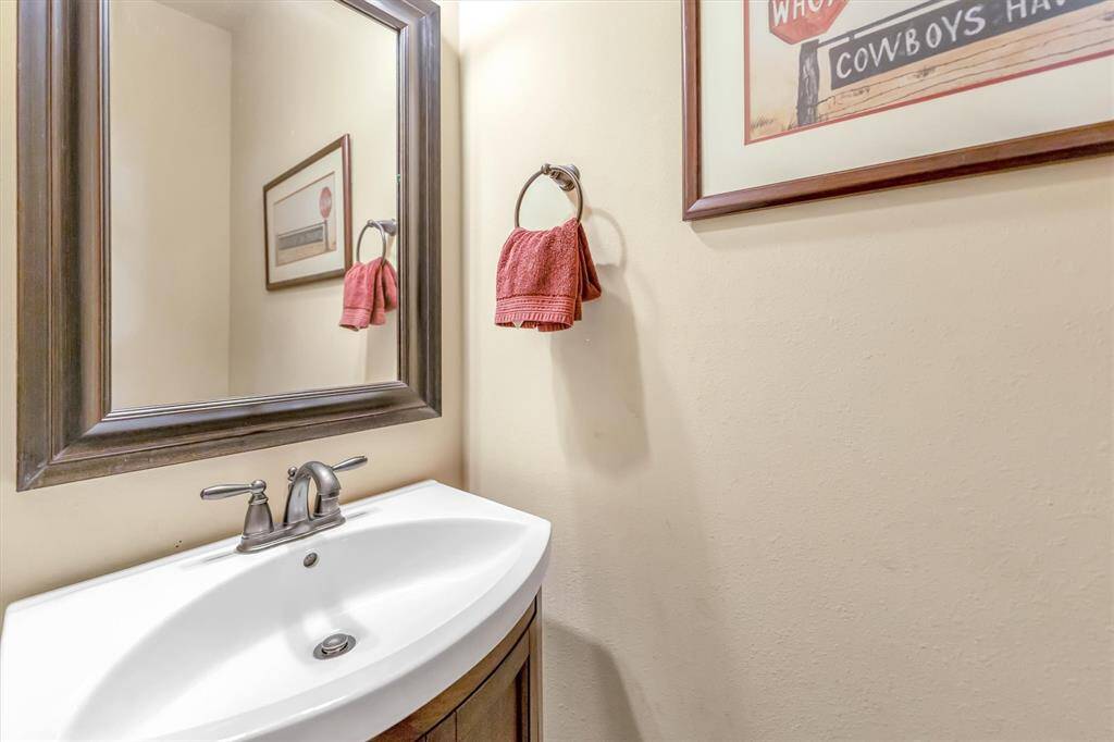 Charming powder room featuring a sleek modern sink, large framed mirror, and soft lighting. Warm, neutral walls are enhanced by tasteful accents.