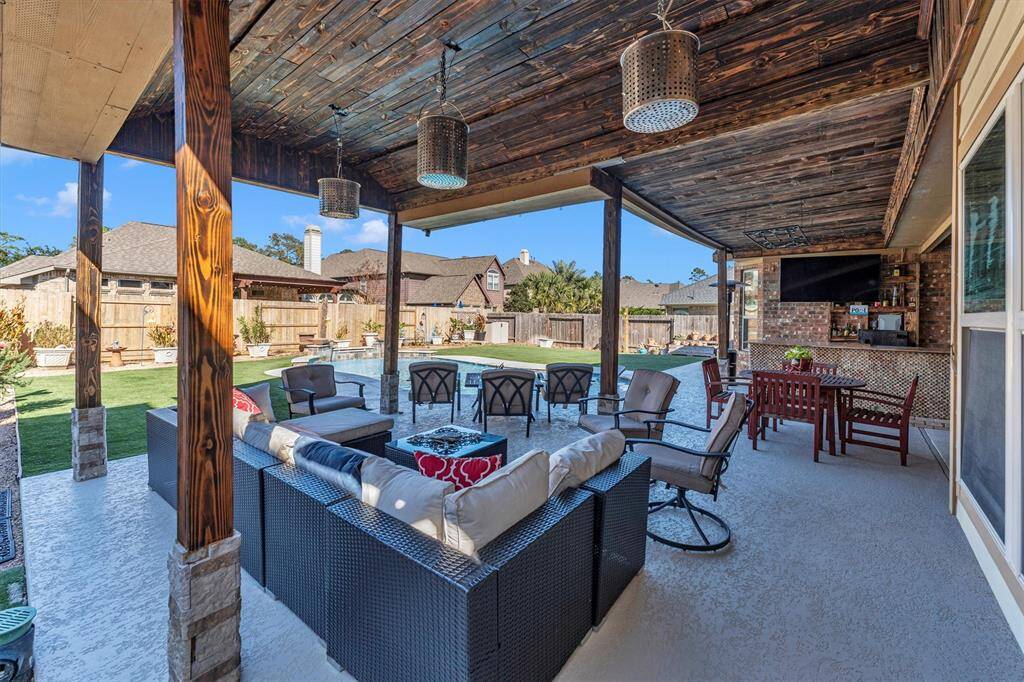 Discover the perfect outdoor oasis with this spacious patio featuring a stylish wooden ceiling, modern furniture, and cozy seating. Enjoy entertaining at the bar with a TV, overlooking a pristine backyard and pool. Ideal for seamless outdoor living.