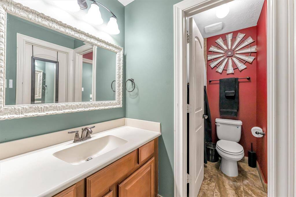Discover a chic bathroom with a sleek vanity, large ornate mirror, and modern lighting. Vibrant walls enhance the elegant fixtures, featuring a unique decorative piece.