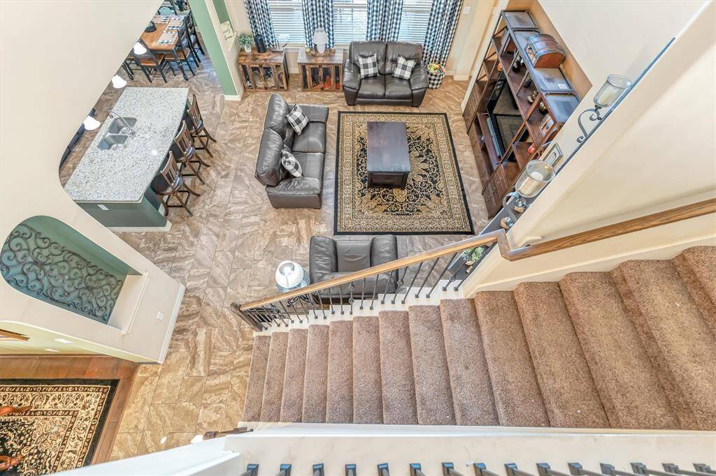 Experience a bright, open-concept living space with stylish leather sofas, a cozy rug, and an entertainment unit. The modern kitchen features a spacious island with bar seating. Enjoy abundant natural light from large windows throughout.
