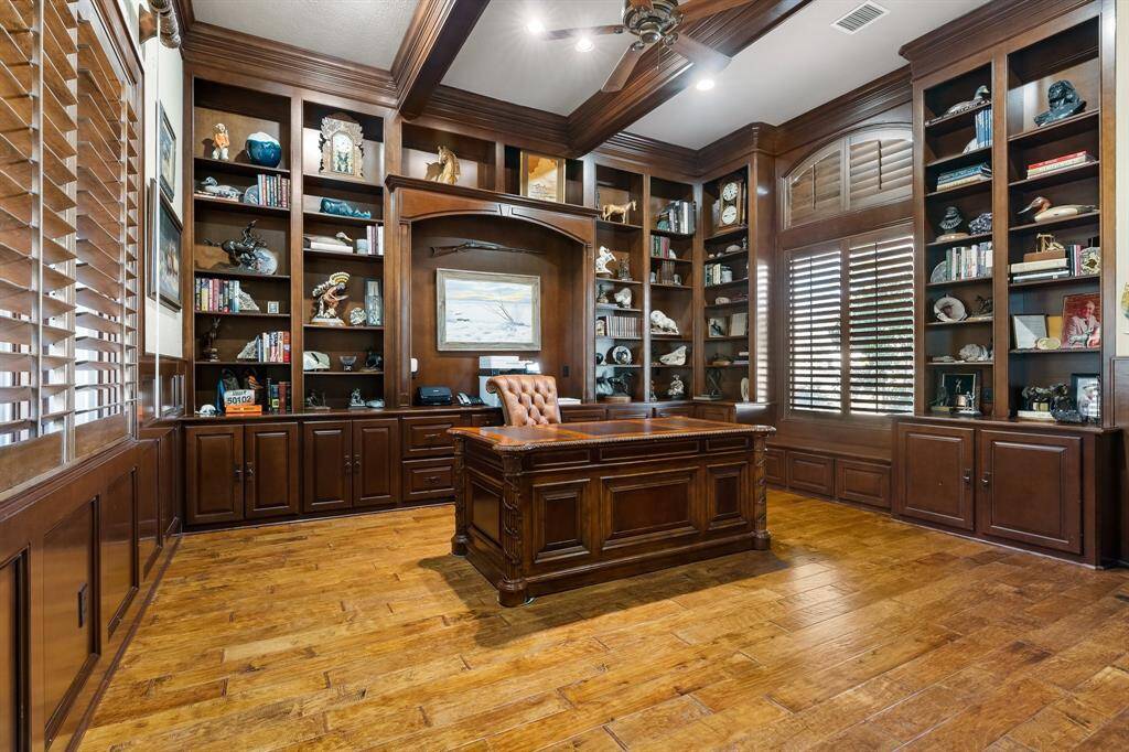 Spacious home office with rich wood finishes, built-in shelving, and ample natural light.