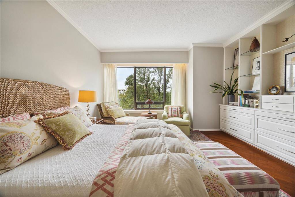 18x17 Primary Bathroom features triple windows with tree top views; wall of custom cabinetry, beautiful wood floors throughout.