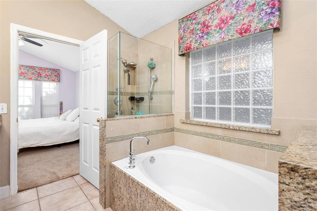 The primary bath offers a separate glass shower and a soaking tub, providing the perfect space to unwind. Immerse yourself in the tub to soak away the day's worries and enjoy a peaceful, rejuvenating experience in your own private retreat.