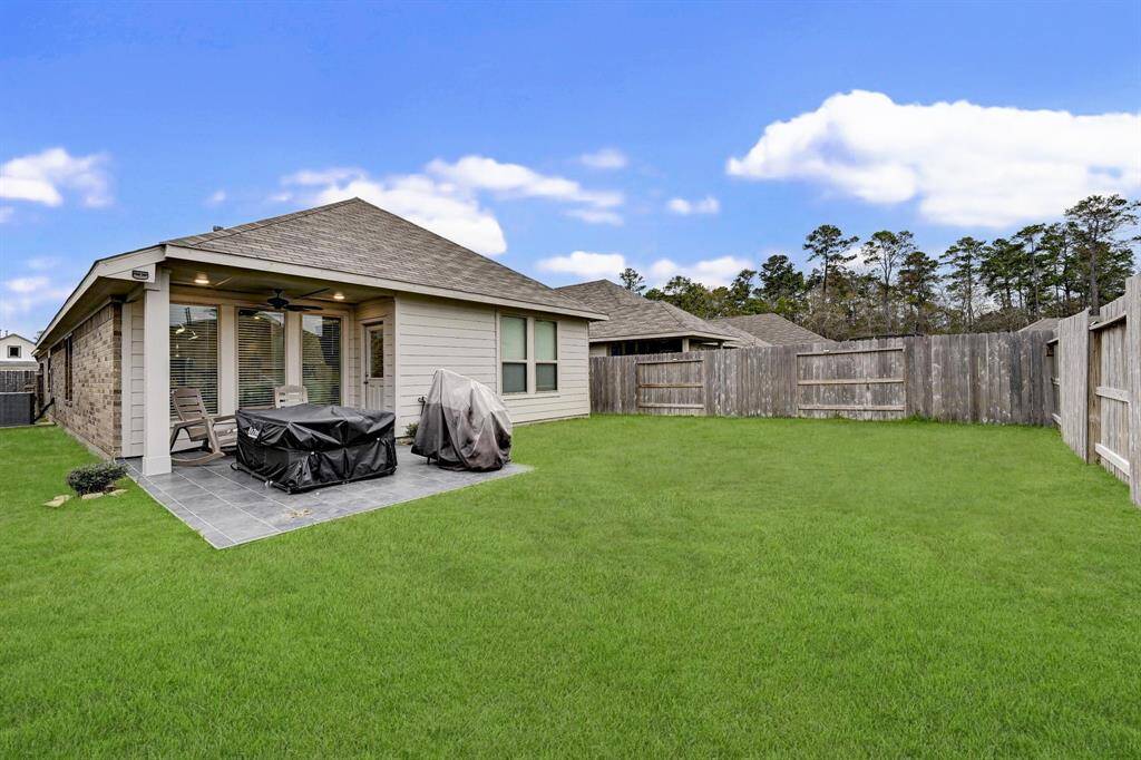 Spacious backyard with a covered patio, perfect for outdoor dining and relaxation. The area is fenced for privacy and features a well-maintained lawn, ideal for families or pets.