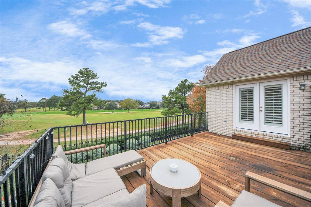 This photo showcases a spacious wooden deck overlooking the golf course. The brick exterior and French doors add charm, providing a serene and picturesque view perfect for relaxation.