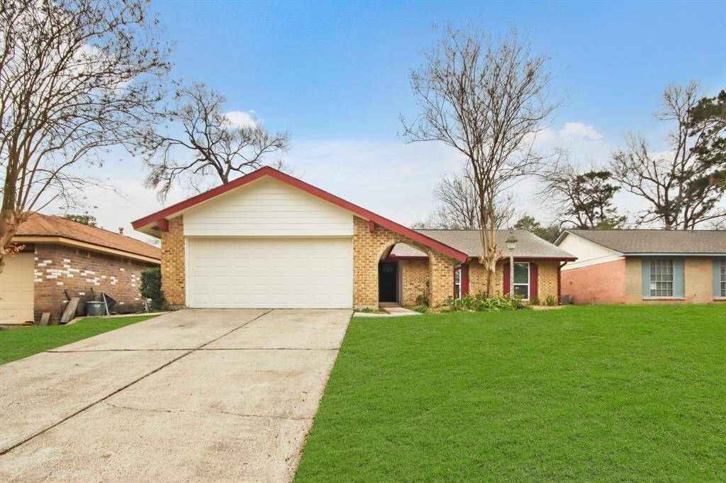 This charming home features a brick facade with a two-car garage, a well-maintained lawn, and a cozy front entrance. It's situated in a quiet neighborhood with mature trees, offering a welcoming atmosphere.