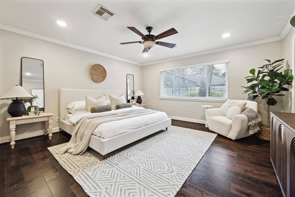 Primary bedroom with views of backyard, recessed lighting and wood floors