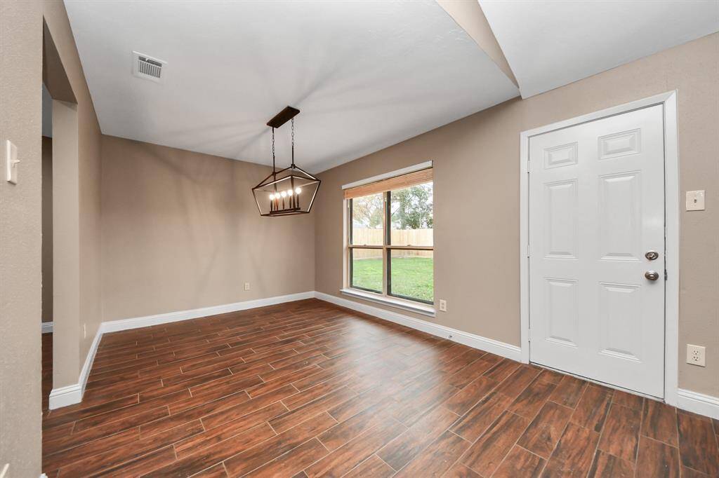 Dining room features updated light fixture and overlooks lush backyard.