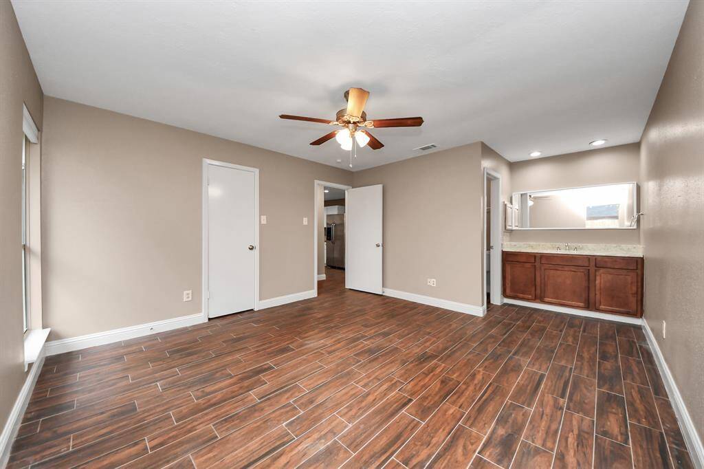 Huge primary bedroom has open vanity and enclosed walk in shower.