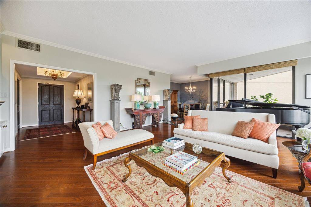 19x23 Living Room.  Beautiful hardwood floors throughout. Walls of windows let light flood the room and offers beautiful views.  Custom cabinetry on the right with electric fireplace.  The mantle and fireplace surround is swathed in silver gilt.