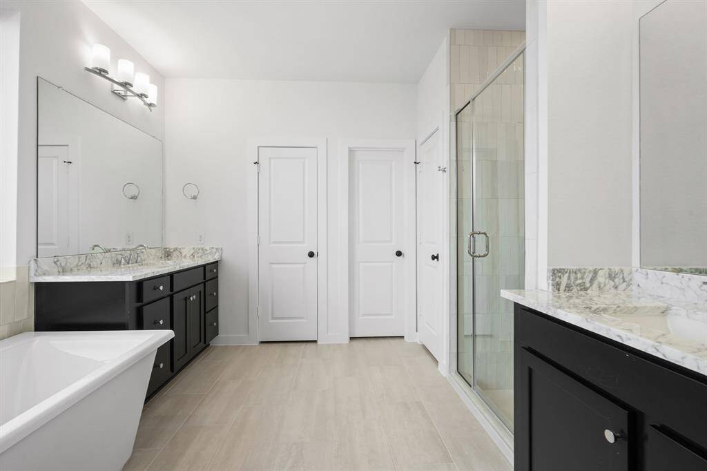 Luxurious main bathroom with a high-end freestanding tub and a glass enlarged shower! Vanities are located on opposite sides of the bathroom for ample space.