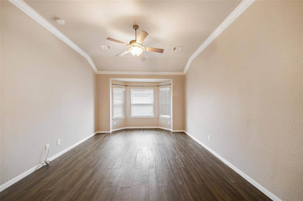 Primary bedroom on first floor has bay window, crown molding and no carpet