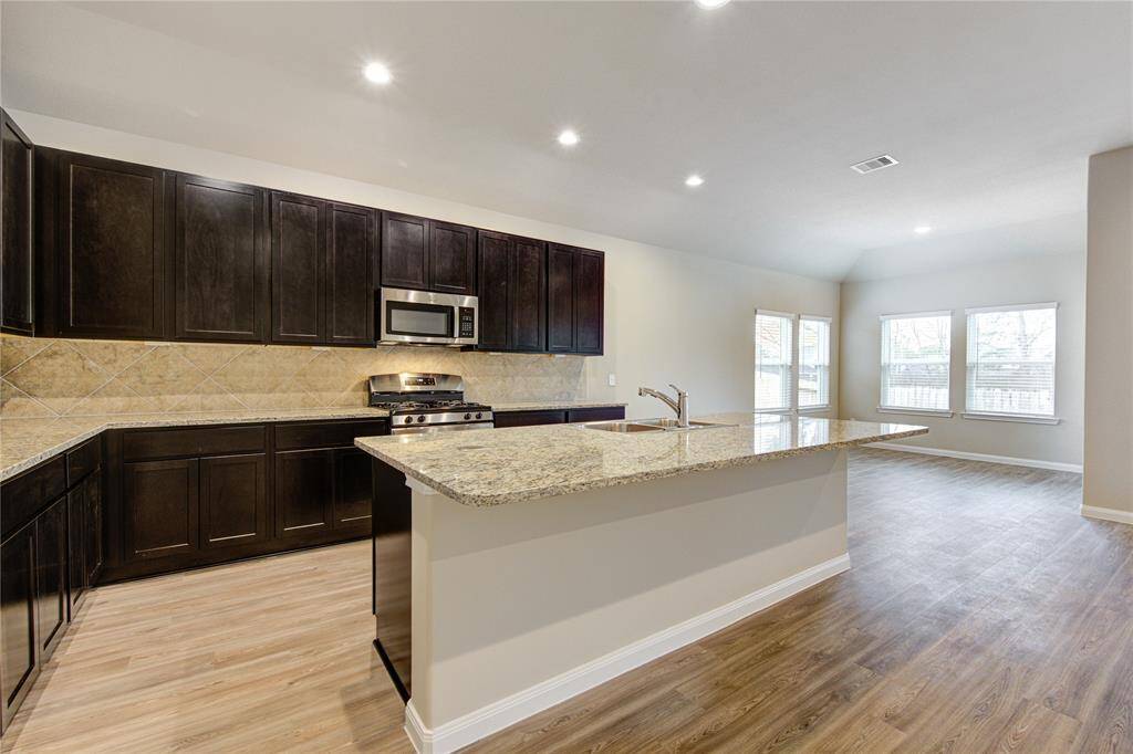 In this kitchen featuring granite counter tops, stainless steel appliances ...