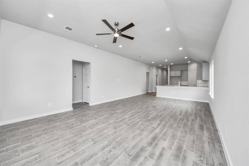 Welcome family and guests to your charming living room! With its high ceilings, recessed lighting, ceiling fan, custom paint, beautiful flooring, and large windows that let in abundant natural light, this room is perfect for gatherings.