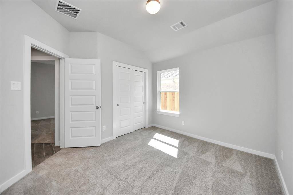 Secondary bedroom features plush carpeting, large windows that let in plenty of natural light, bright paint, and spacious closets.