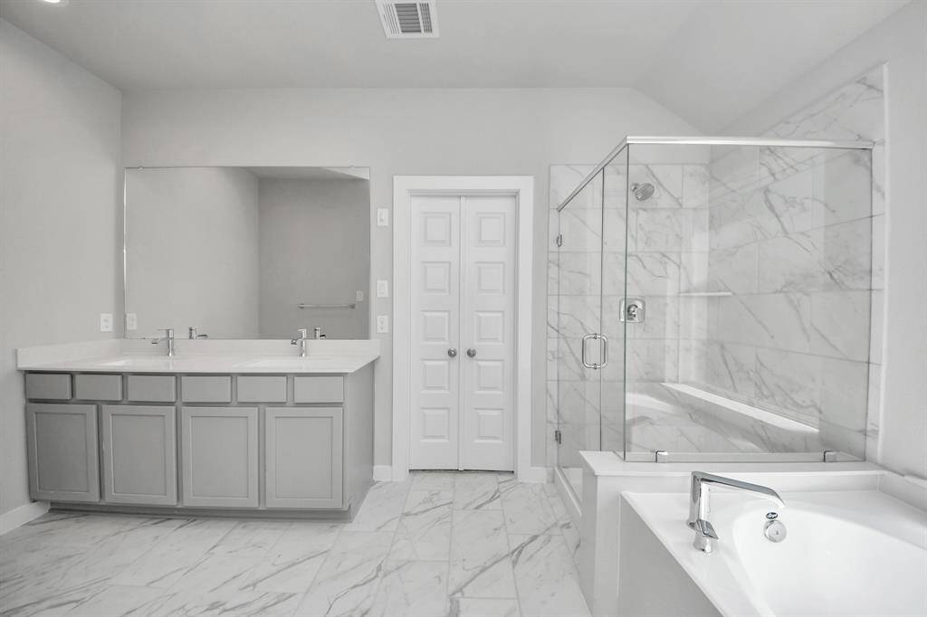 Escape to a spa-like oasis in this primary bathroom. Enjoy a walk-in shower with tile surround, a separate garden tub with custom detailing, and an elegant vanity featuring light countertops, modern hardware, and beautiful recessed lights. Experience luxury and relaxation in every detail