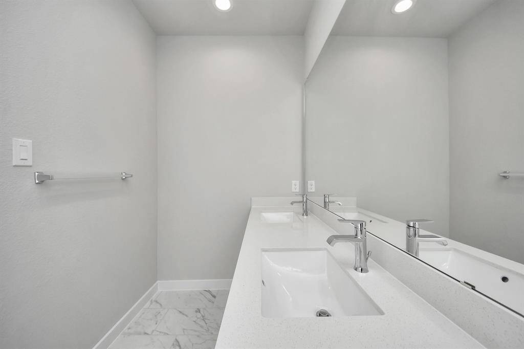 Elevate your daily routine at the elegant vanity, now equipped with double sinks, light countertops, modern hardware, and beautiful recessed lights.