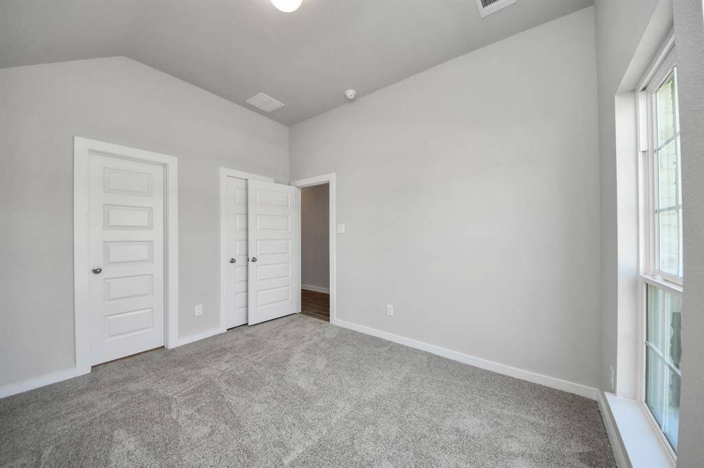 Inviting guest suite adorned with modern charm. The room features elegant 5-panel doors with sleek, contemporary hardware that adds a touch of sophistication. Sink your feet into the plush, fluffy carpet that invites comfort and warmth. Large windows flood the space with an abundance of natural light, framed by privacy blinds that offer the perfect balance between openness and seclusion.