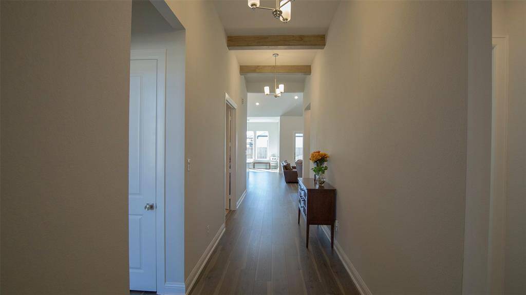 A spacious hallway with luxury flooring leads to an open living area with large windows, creating a bright and inviting space.  Secondary bedrooms, media room, and the bathroom for your guest are accessible from this hallway.