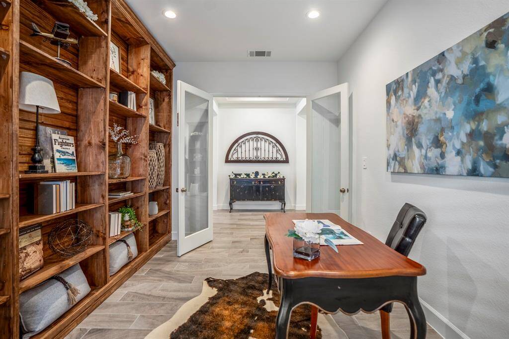This is a beautifully designed home office space that combines functionality with aesthetic appeal. Floor-to-ceiling custom Built-in wooden shelving provides ample storage and display space for books, decorative items, and personal touches. Frosted glass French doors allow privacy while letting light flow through, maintaining a sense of openness.