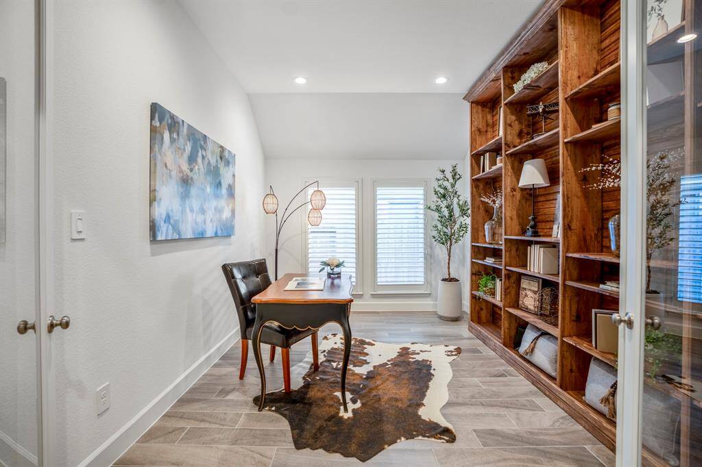 A classic wooden desk with a dark finish and curved detailing serves as the centerpiece of the workspace. The warm wood tones add a cozy and natural feel to the room. This home office is both inviting and practical, offering an inspiring environment for productivity while showcasing tasteful design elements.