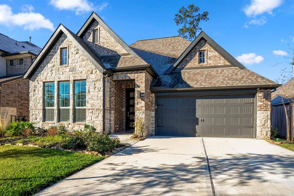 A two-car garage with a dark-toned door complements the home's color palette and provides ample parking and storage.
