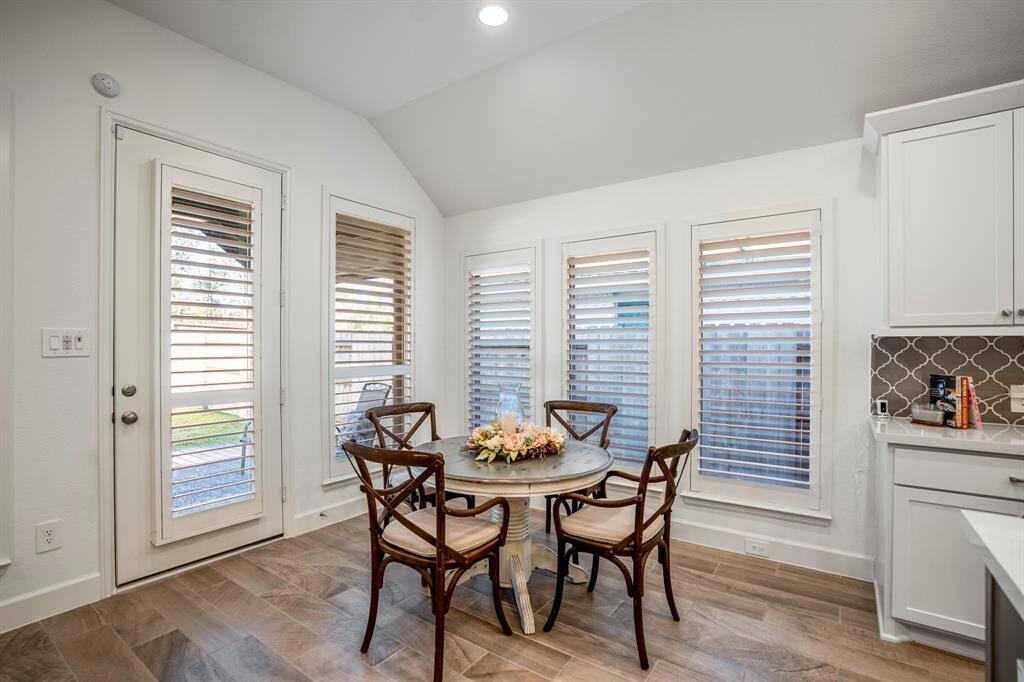 A rustic-style round dining table surrounded by wooden chairs with cushioned seats, creating a cozy spot for meals.