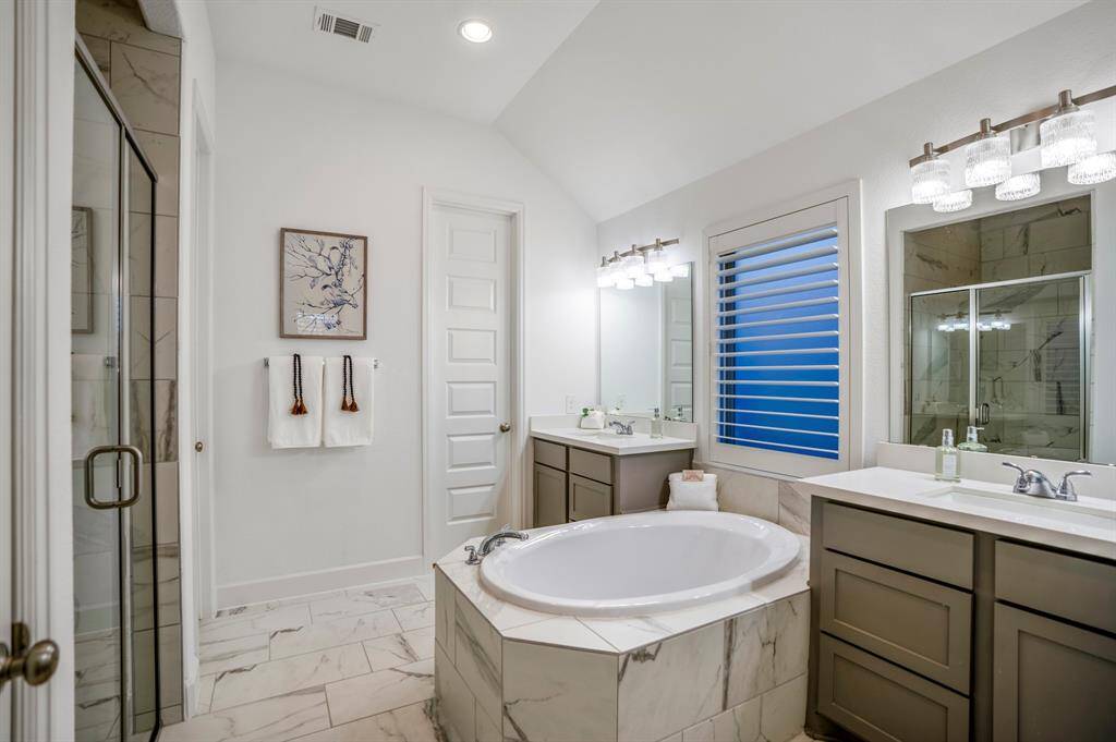 This is a luxurious and elegant primary bathroom, designed for relaxation and functionality. A spacious soaking tub with a marble-tile surround, creating a serene and spa-like focal point.
