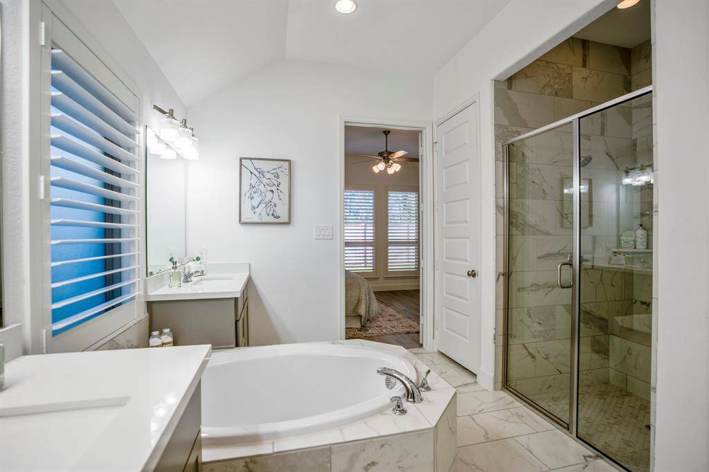 Two separate vanities with gray cabinetry and white countertops, offering plenty of storage and personal space.Large framed mirrors above each vanity, accompanied by modern light fixtures with glass shades for a bright, polished look.