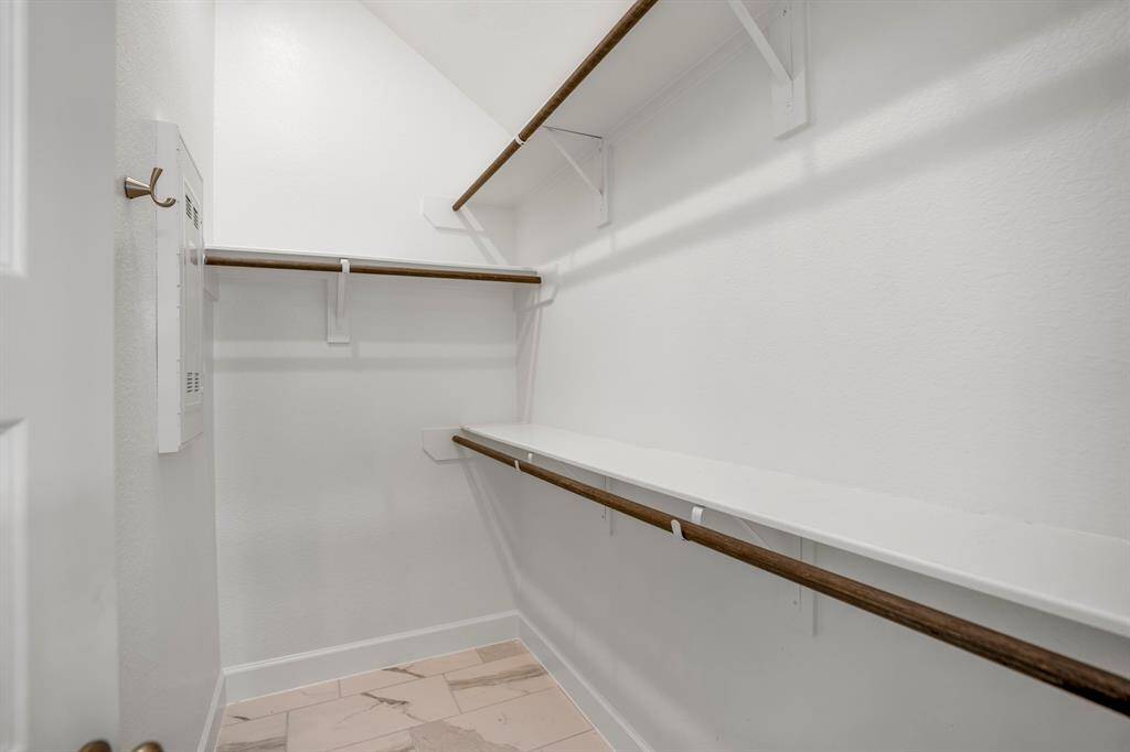 This primary ensuite boast two walk-in closets.  The clean, white finish ensures a bright and fresh look. Multiple sturdy rods, framed with white brackets, provide ample space for hanging clothes of varying lengths.