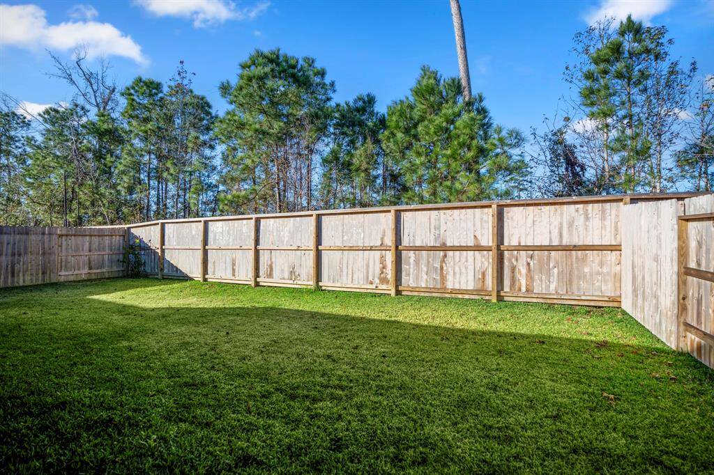 A wooden privacy fence encloses the backyard, ensuring a peaceful and secure environment. The space overlooks trees beyond the fence, enhancing the serene atmosphere with a touch of nature.