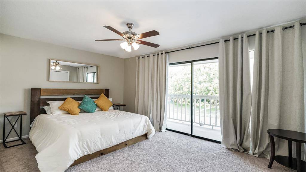 The first bedroom has carpet floors, a ceiling fan and sliding glass doors to gain access to the balcony.