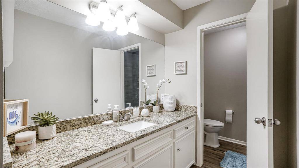 The en-suite bathroom for the first bedroom has laminate wood floors and granite counters.