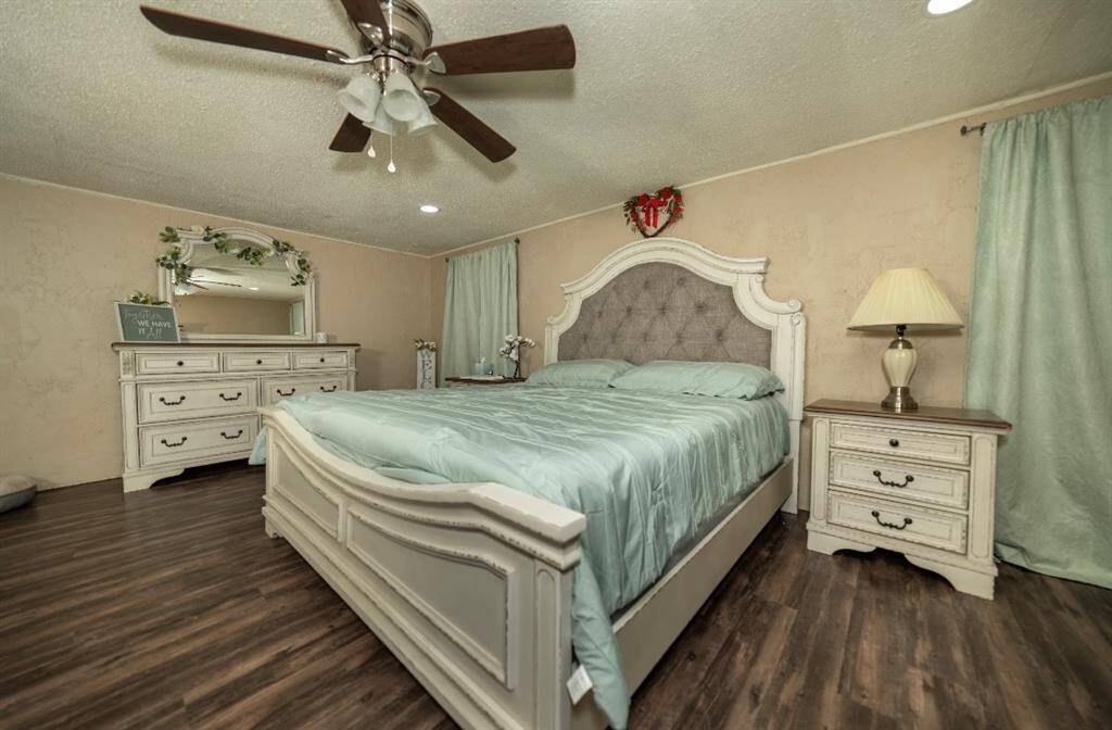 This spacious bedroom features vinyl floors, a ceiling fan, and recessed lighting.
