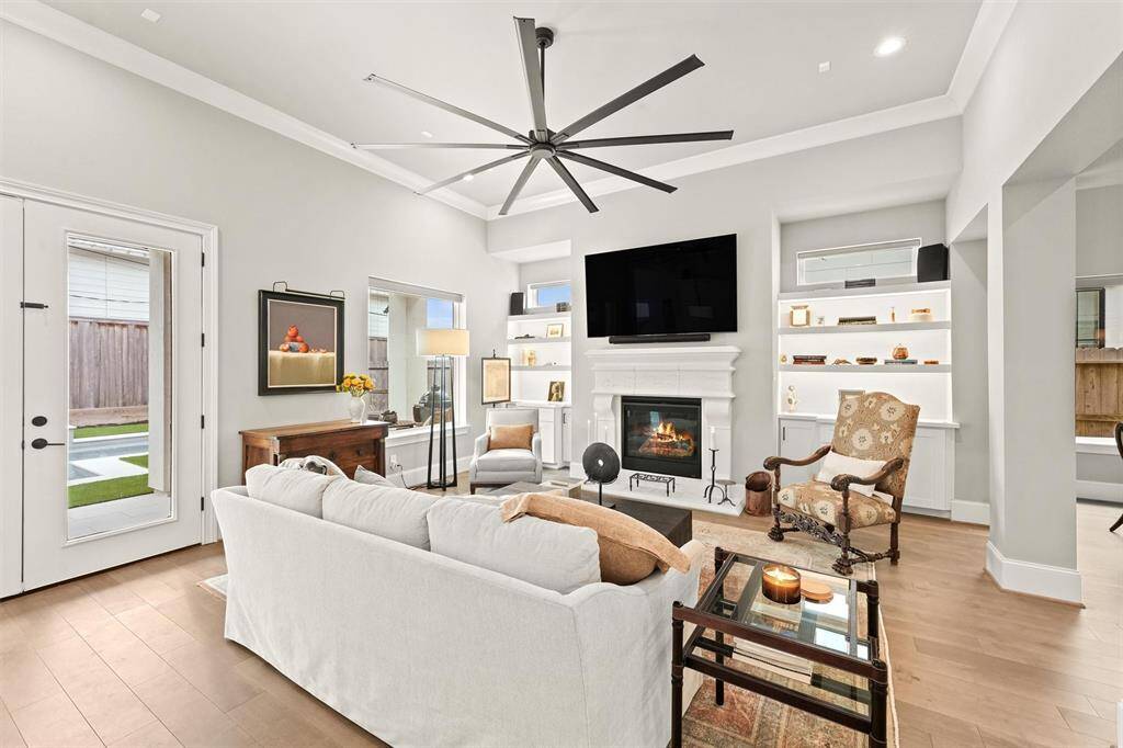 The gaslog fireplace is flanked by two sets of custom cabinets and open shelving, accented with undercabinet custom LED lighting. The windows (even the transom windows!) have motorized light-filtering shades from The Shade Store®.