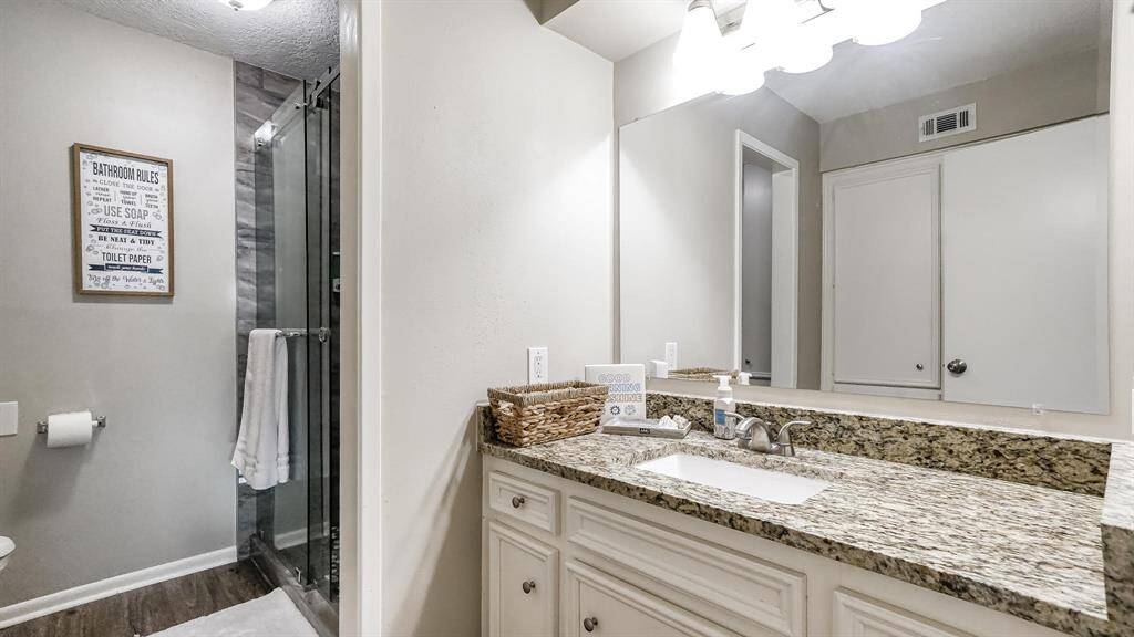 The second and third bedroom share this bathroom which features laminate wood floors, granite counters and a standing shower with tile surround and sliding glass door.