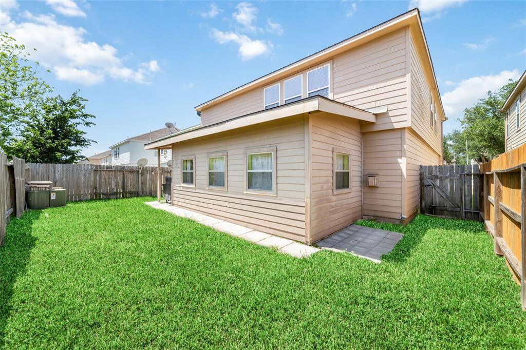 This is a two-story home featuring a well-maintained lawn and a fenced backyard with a small patio area, providing a private outdoor space for relaxation and activities.