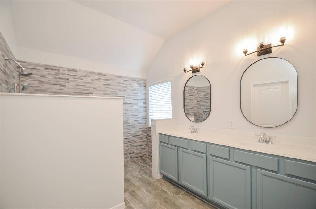 Don't you love the robin's egg blue tone on cabinetry below dual sinks and individual contemporary mirrors and delicate lighting above, in the primary bath?