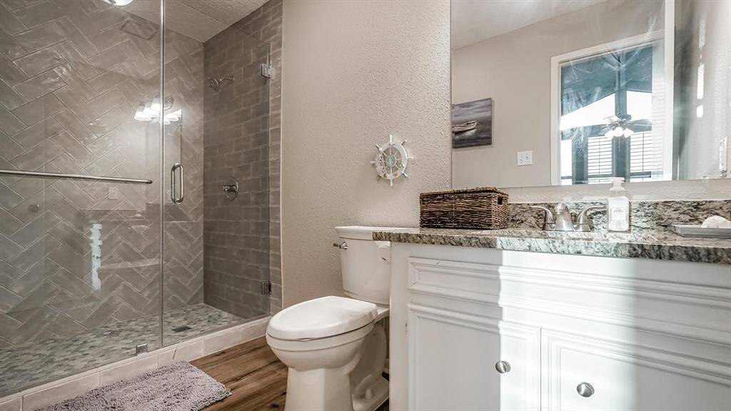 The third full bathroom has laminate wood floors, granite counters and a standing shower with tile surround and a seamless glass door.
