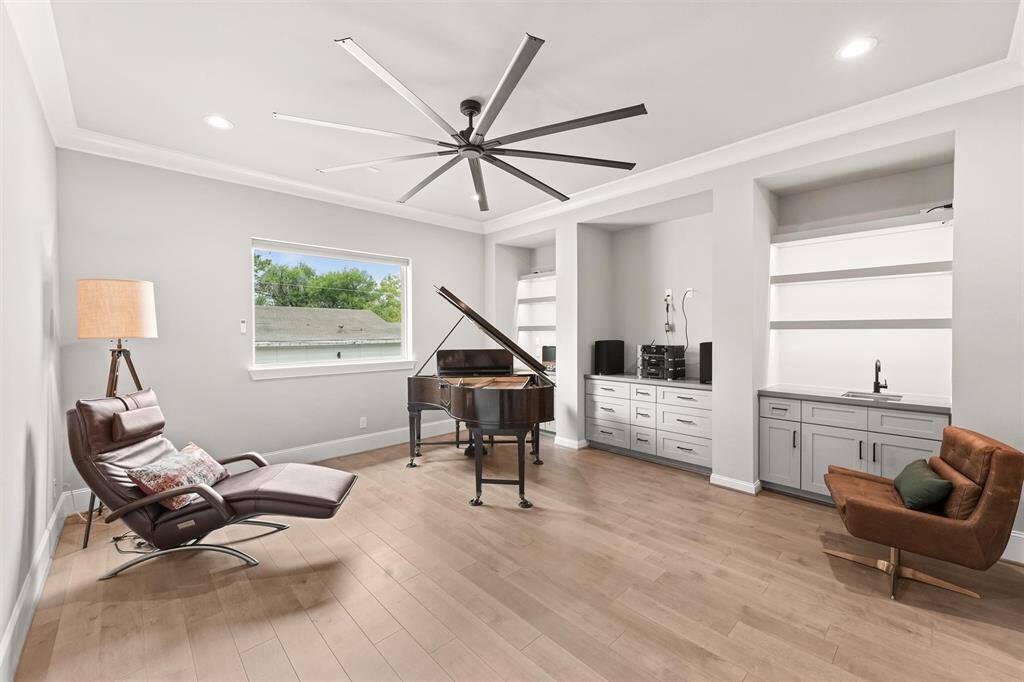 Upstairs is the sizable gameroom, featuring a wet bar; cabinetry and open shelving; and color-changing LED undercabinet lighting.